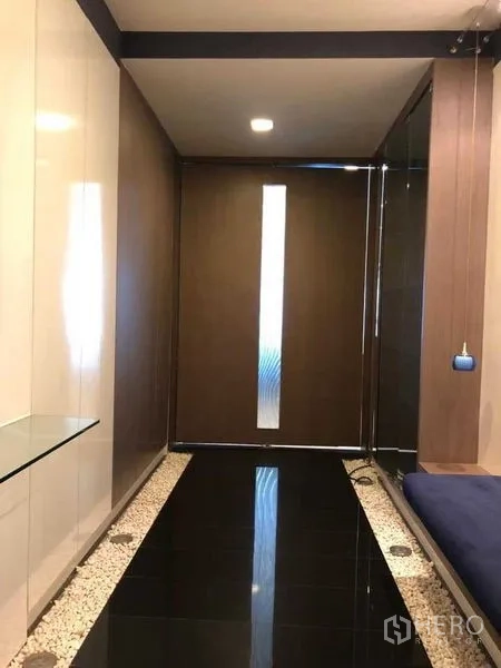 公寓 出租在Khlong Luang, Pathum Thani - 玄关走廊，深色地面与木质装饰墙。