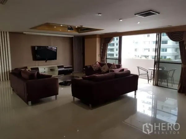 คอนโด ให้เช่าหรือขายในWatthana, Bangkok - ห้องนั่งเล่นสว่างพร้อมโซฟาสีไวน์แดง เปิดสู่ระเบียงมีวิวเมืองและชุดโต๊ะกลางแจ้ง
