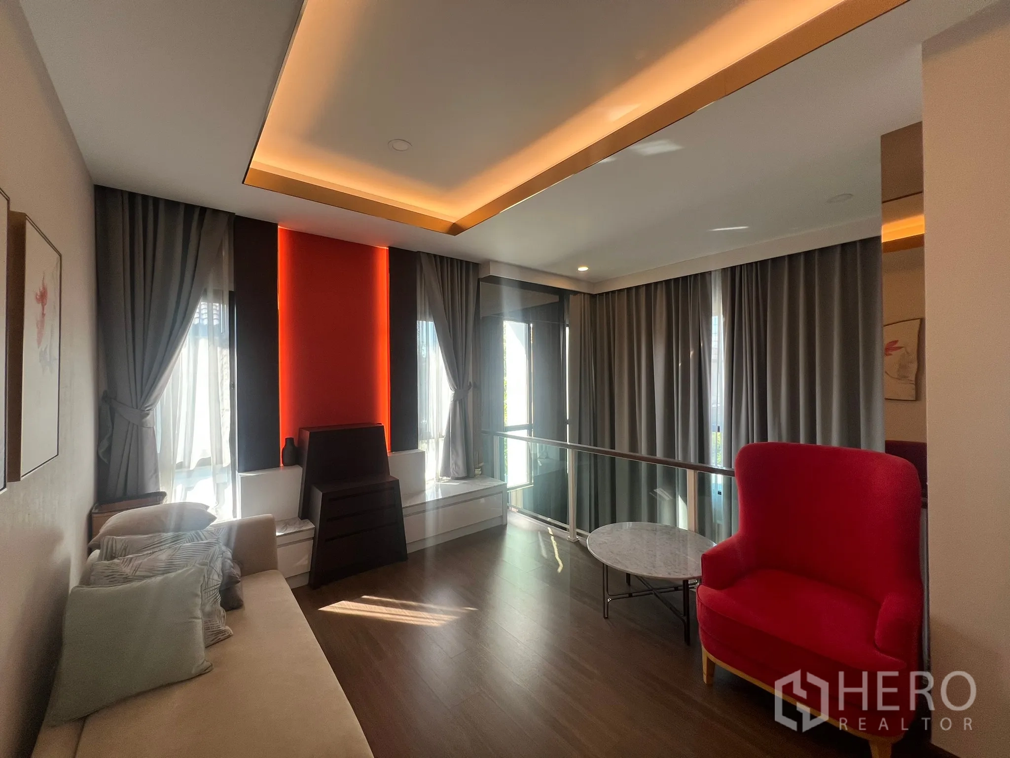 Detached House for rent or sale in Prawet, Bangkok - Upstairs sitting area with red armchair, marble coffee table and soft lighting.