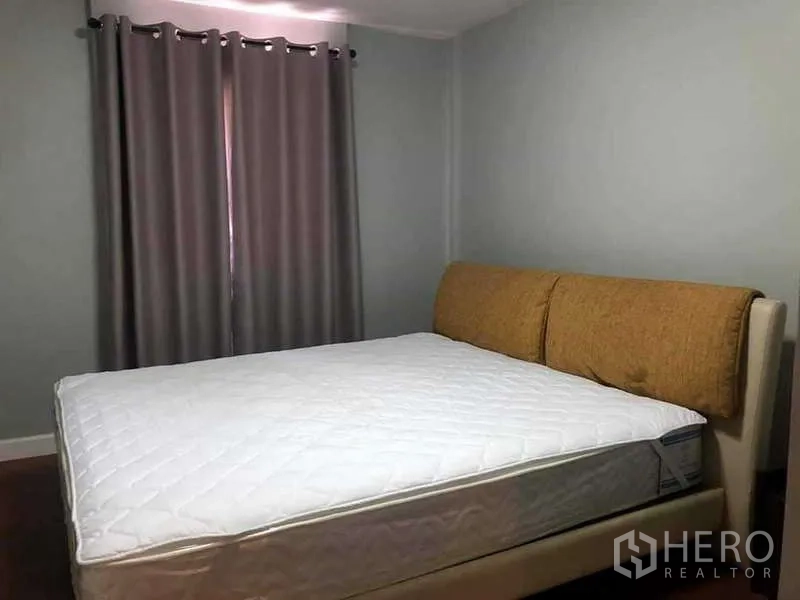 Condominium for sale in Yan Nawa, Bangkok - Primary bedroom with upholstered headboard, gray curtains and wood flooring.