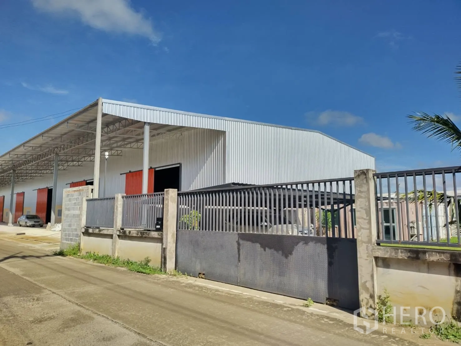 仓库 for rent in Khlong Luang, Pathum Thani - 围栏与大门一侧的仓库角度，可见屋顶连廊和临街出入口