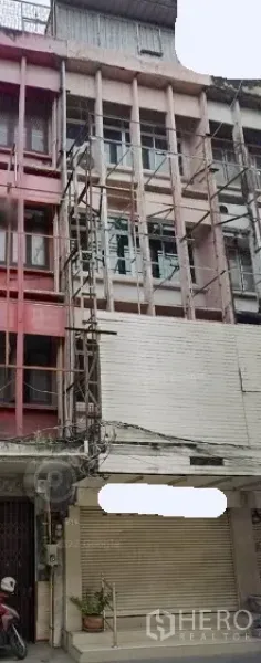 Shophouse for rent in Khlong Toei, Bangkok - Four-storey shophouse facade on Sukhumvit with scaffolding and a closed roller shutter.
