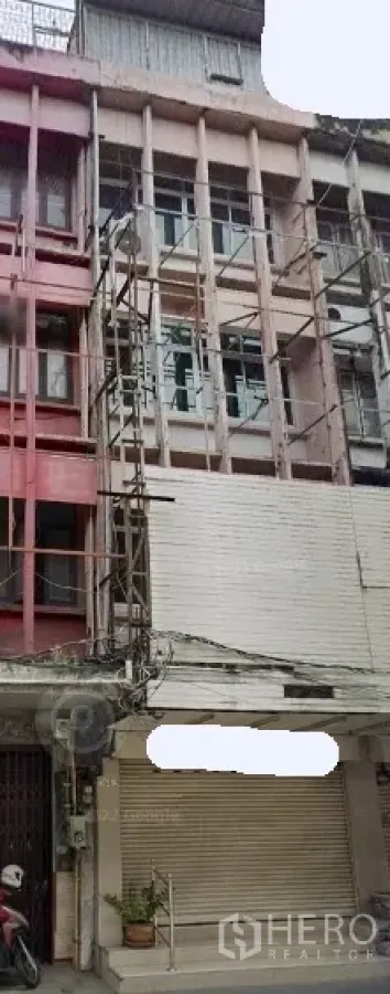 Shophouse for rent in Khlong Toei, Bangkok - Four-storey shophouse facade on Sukhumvit with scaffolding and a closed roller shutter.