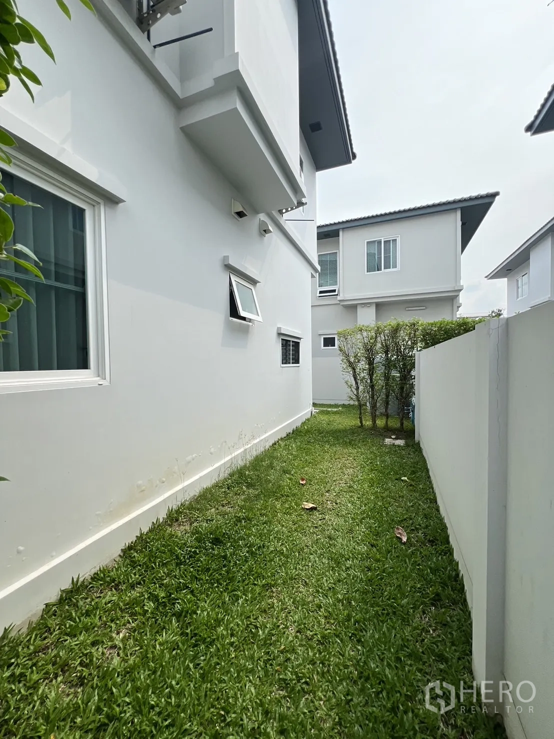 独立式住宅 出租在Prawet, Bangkok - 后侧草坪沿白色围墙延伸，活动空间增加。