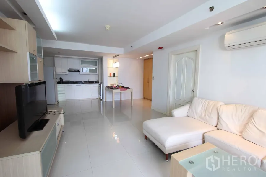 คอนโด ให้เช่าในWatthana, Bangkok - ห้องนั่งเล่นสว่างพร้อมโซฟาเข้ามุมสีขาว ชั้นวางทีวี และครัวบิวท์อินพร้อมโต๊ะอาหาร