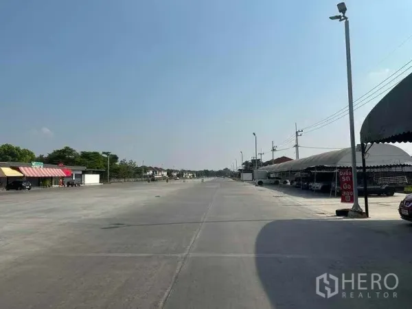 Retail Space for rent in Pathum Thani - Expansive paved area with tented stalls on the right and shopfronts on the left, ideal for parking.