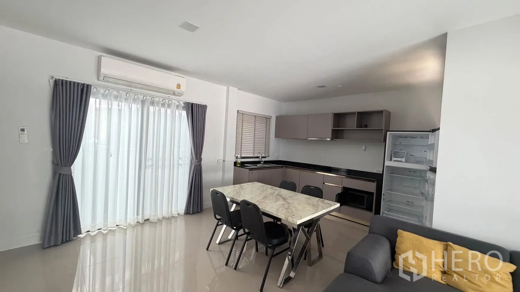Townhouse for rent in Bang Phli, Samut Prakan - Open-plan kitchen with L-shaped cabinets, marble dining table, and refrigerator.