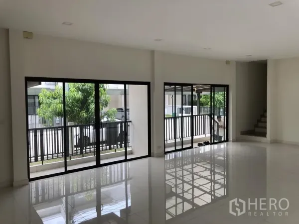 Townhouse for rent or sale in Saphan Sung, Bangkok - Bright open-plan living area with glossy tile floors and large sliding glass doors.