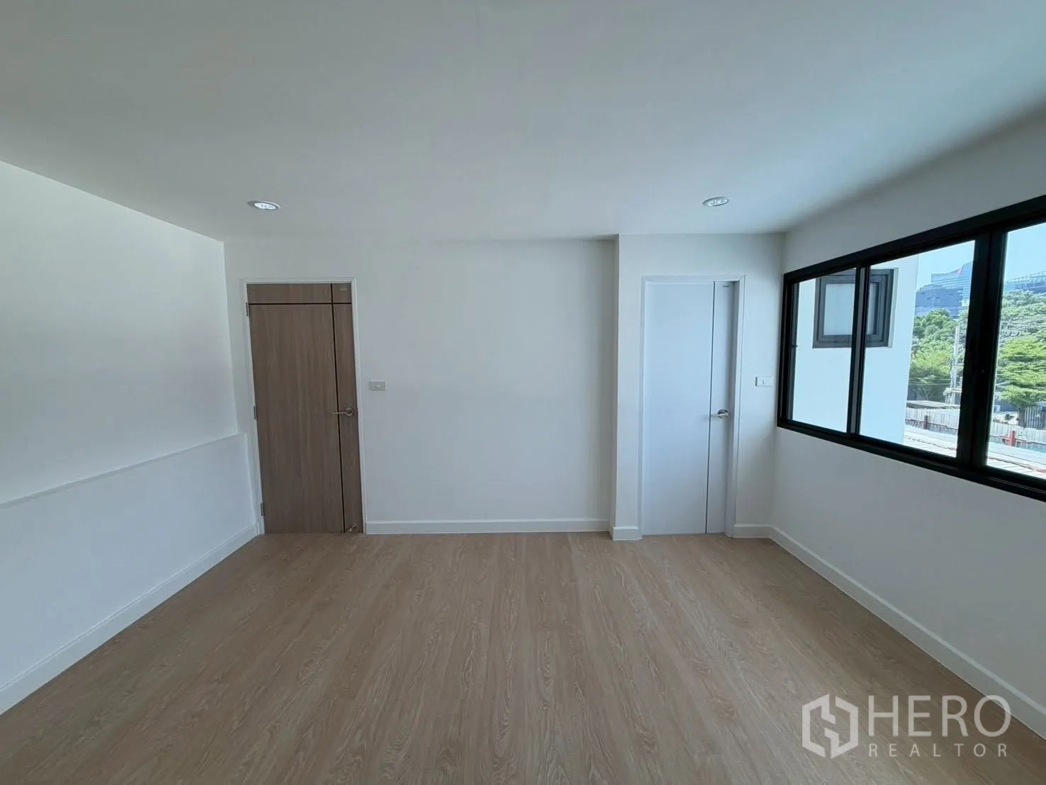 Townhouse for sale in Phra Khanong, Bangkok - Sunlit room with wood doors and wide windows.