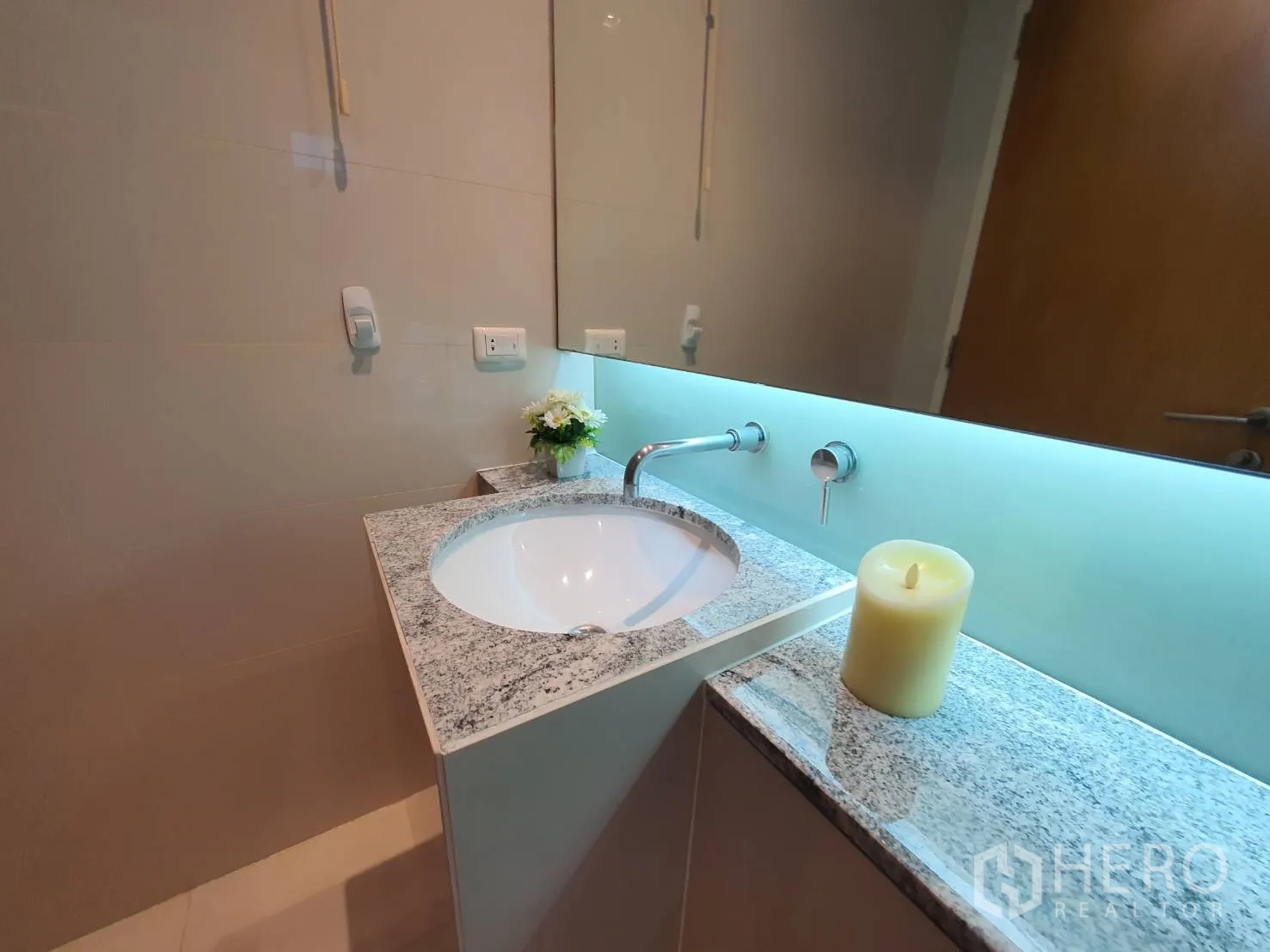 Condominium for rent in Khlong Toei, Bangkok - Guest bathroom with granite vanity, round basin and a soft backlit mirror.