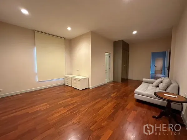 Detached House for rent or sale in Khan Na Yao, Bangkok - Spacious room with warm wooden flooring, recessed lighting and sofa seating.