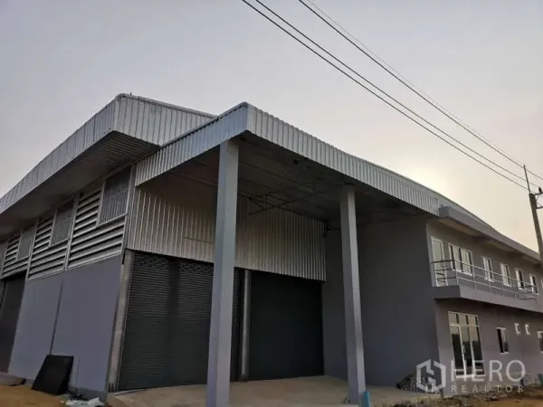 货栈 出租在Khlong Luang, Pathum Thani - 仓库外观，带雨棚装卸区、卷闸门与一体式办公楼，位于空銮县。