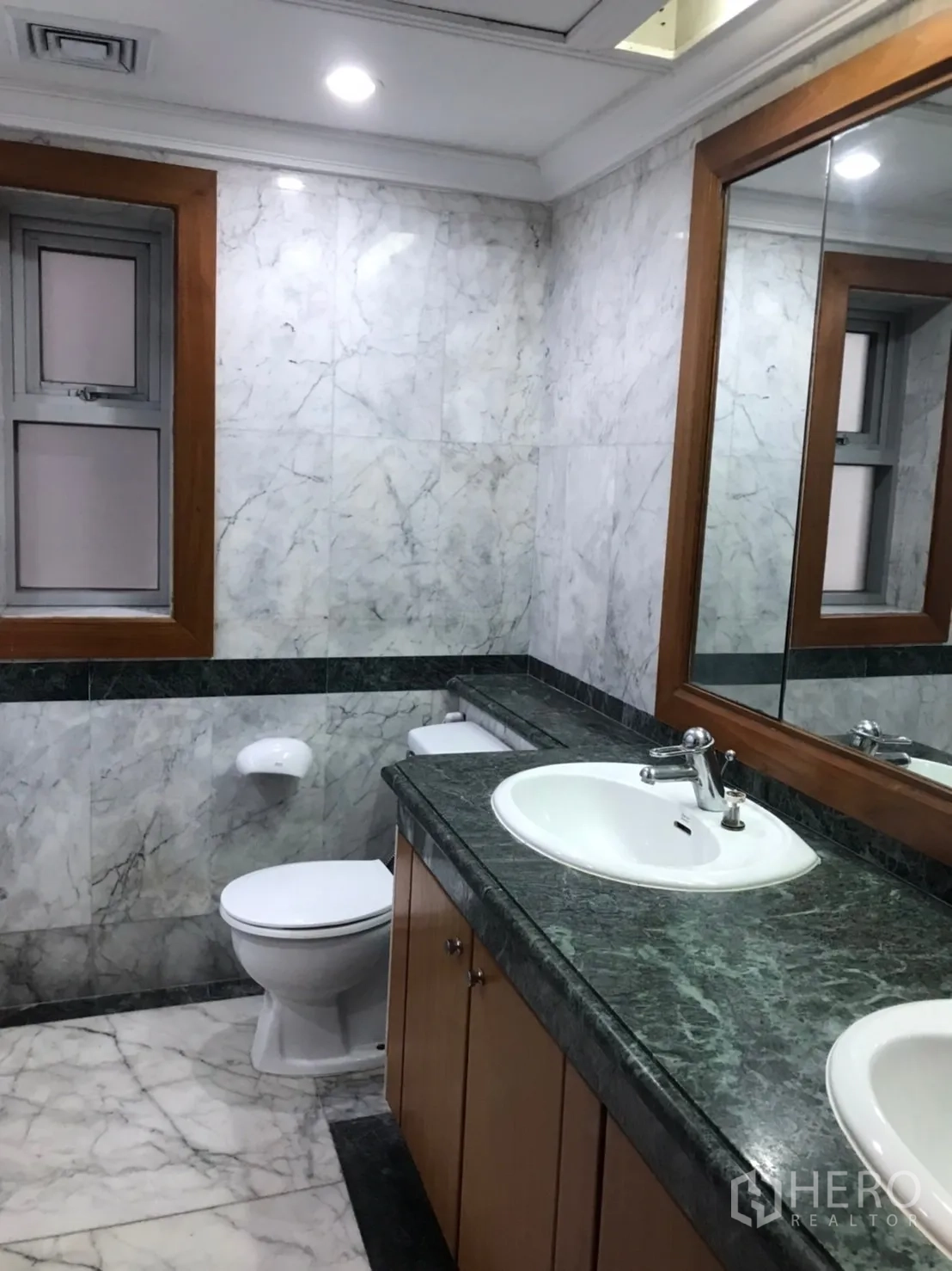 公寓 出租或出售在Pathum Wan, Bangkok - 浴室设大理石墙面、长石台盆、超大镜面与坐便器。