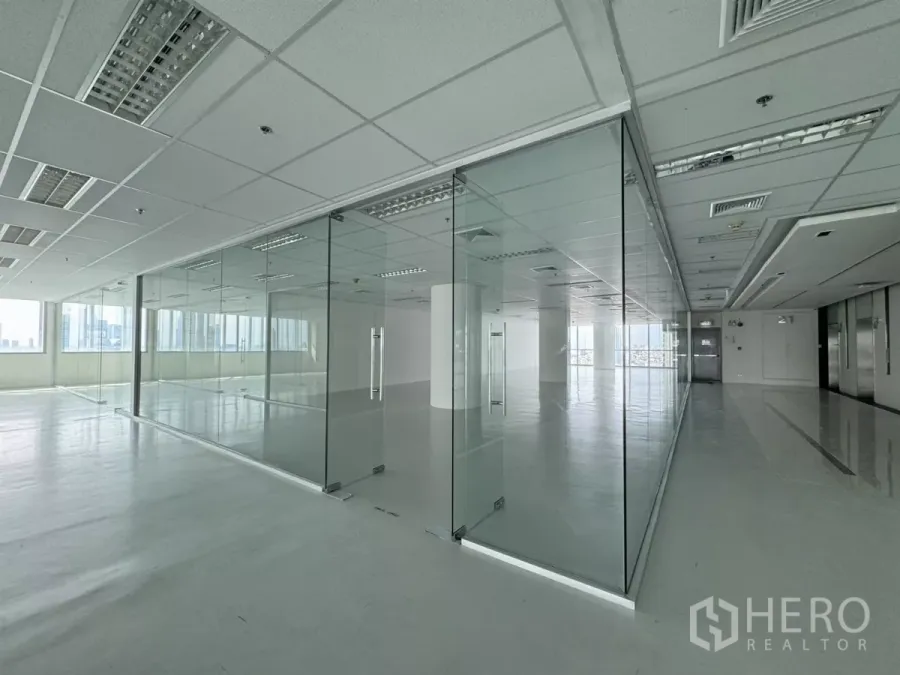 办公空间 出租在Sathon, Bangkok - 明亮的开放式办公室，玻璃隔断会议室与网格吊顶照明，窗外可见城市景观，邻近BTS圣路易站，位于曼谷沙吞。