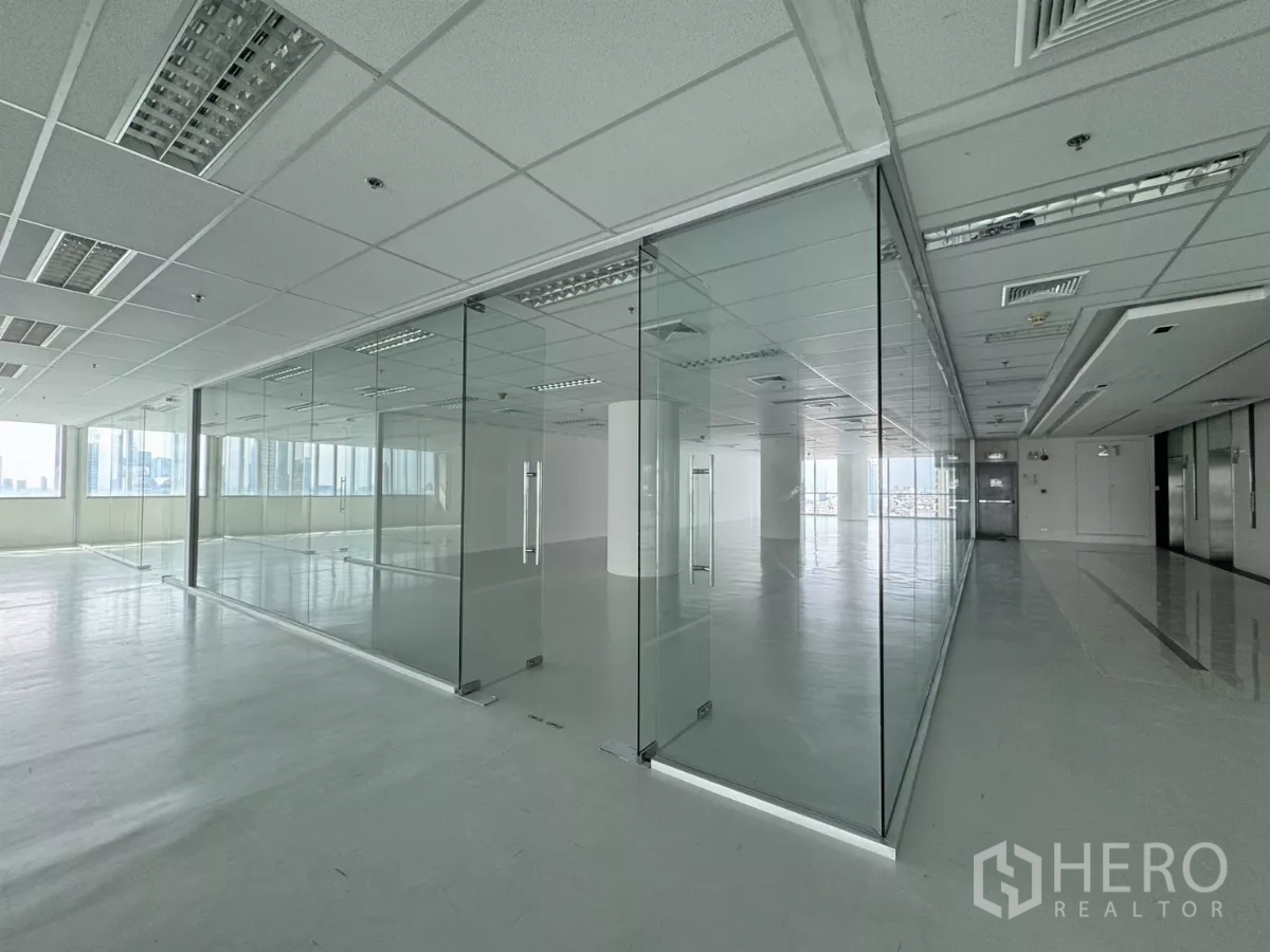 办公空间 出租在Sathon, Bangkok - 明亮的开放式办公室，玻璃隔断会议室与网格吊顶照明，窗外可见城市景观，邻近BTS圣路易站，位于曼谷沙吞。