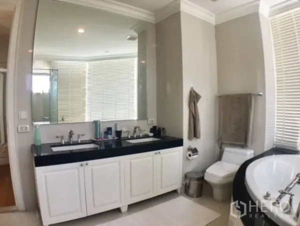 Condominium for rent in Watthana, Bangkok - Spacious bathroom featuring a double-sink vanity, large mirror, soaking tub and toilet.
