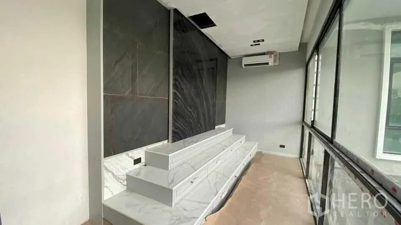 独立式住宅 出售在Mueang Nonthaburi, Nonthaburi - 大理石电视柜与黑色石材景墙，旁为落地窗与空调。