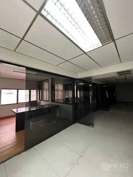 Office Space for rent in Pathum Wan, Bangkok - Corridor of tinted-glass private offices with overhead lighting.