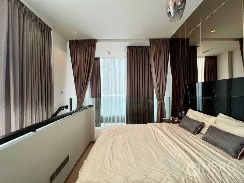Condominium for rent - Mezzanine bedroom with glass balustrade, floor-to-ceiling curtains and soft lighting.