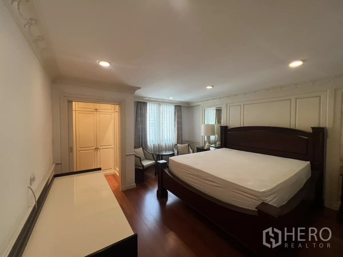 Townhouse for sale in Watthana, Bangkok - Bedroom with king bed, seating corner and walk-in wardrobe.