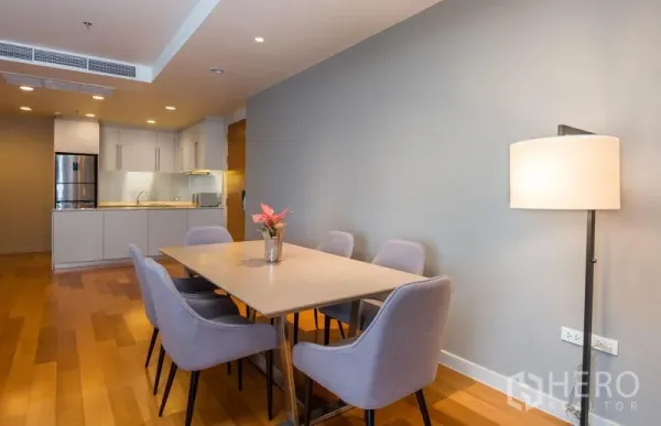 Condominium for rent in Bang Kho Laem, Bangkok - Dining area for six beside a modern open kitchen with wood floors and soft downlights.