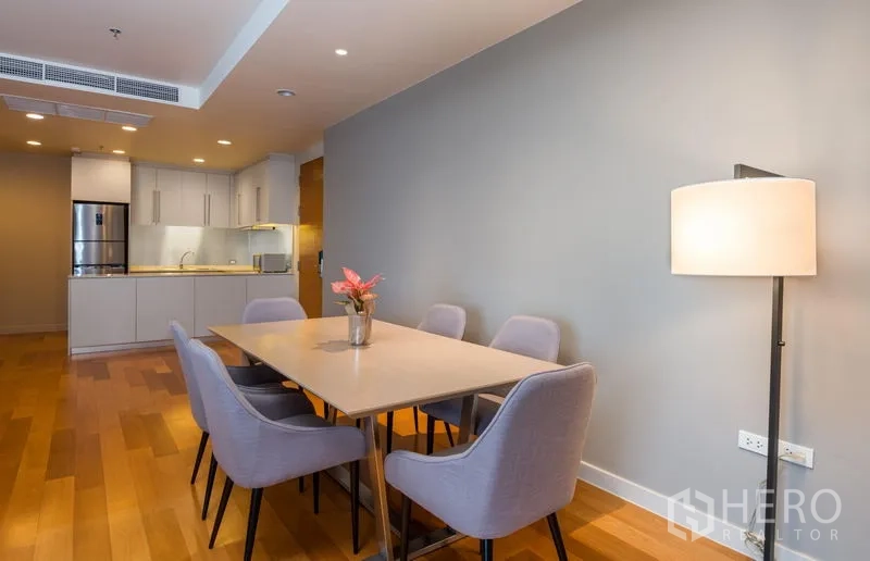 Condominium for rent in Bang Kho Laem, Bangkok - Dining area for six beside a modern open kitchen with wood floors and soft downlights.