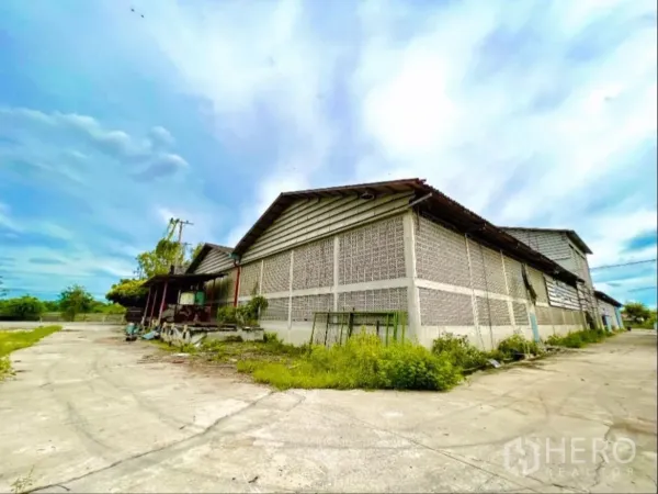Factory for rent in Sai Noi, Nonthaburi - Corner view of the factory exterior with ventilation block walls and a side service lane.