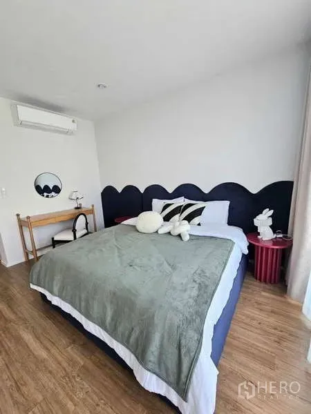 Townhouse for rent in Suan Luang, Bangkok - Cozy bedroom with upholstered headboard, work desk, air conditioner and wood flooring.