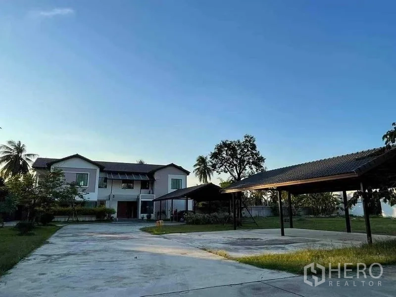 Warehouse for sale in Chon Buri - Expansive courtyard with covered carports and a two-storey office building in the background.