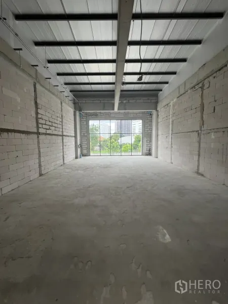 零售空间 出租在Khlong Toei, Bangkok - 毛坯零售空间，水泥地、砖墙、高金属顶，尽头为大型窗户。