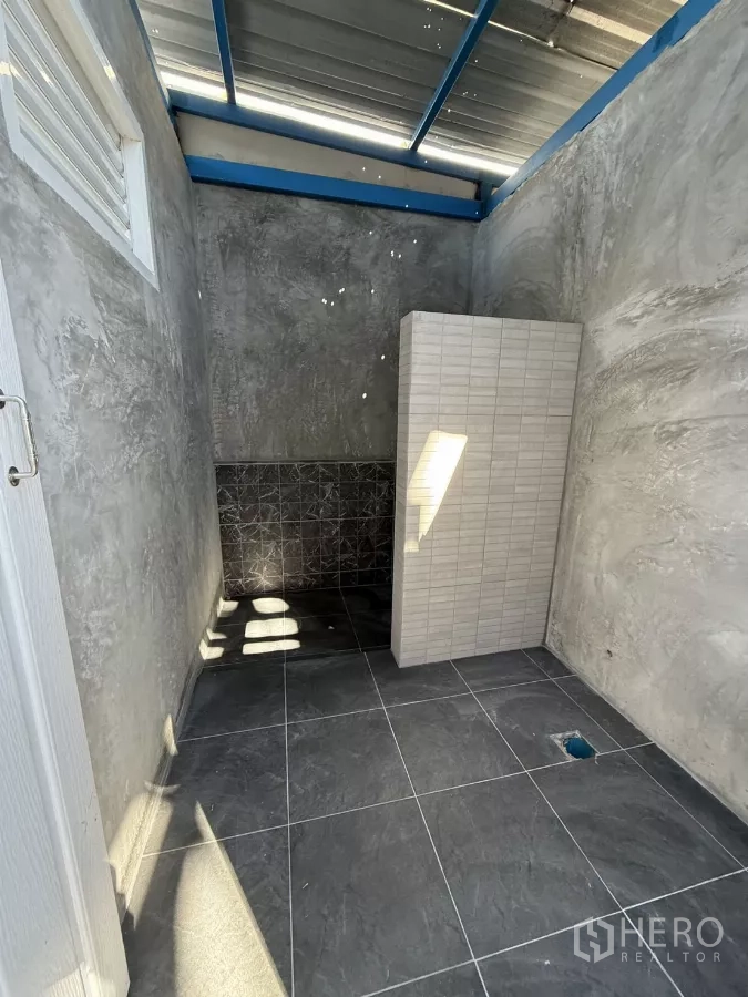 Warehouse for rent in Lam Luk Ka, Pathum Thani - Clean tiled restroom with partial wall divider and natural light from a vent.