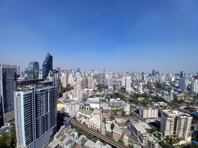 Condominium for rent in Khlong Toei, Bangkok - High-rise Bangkok city skyline view with BTS line under a clear blue sky.
