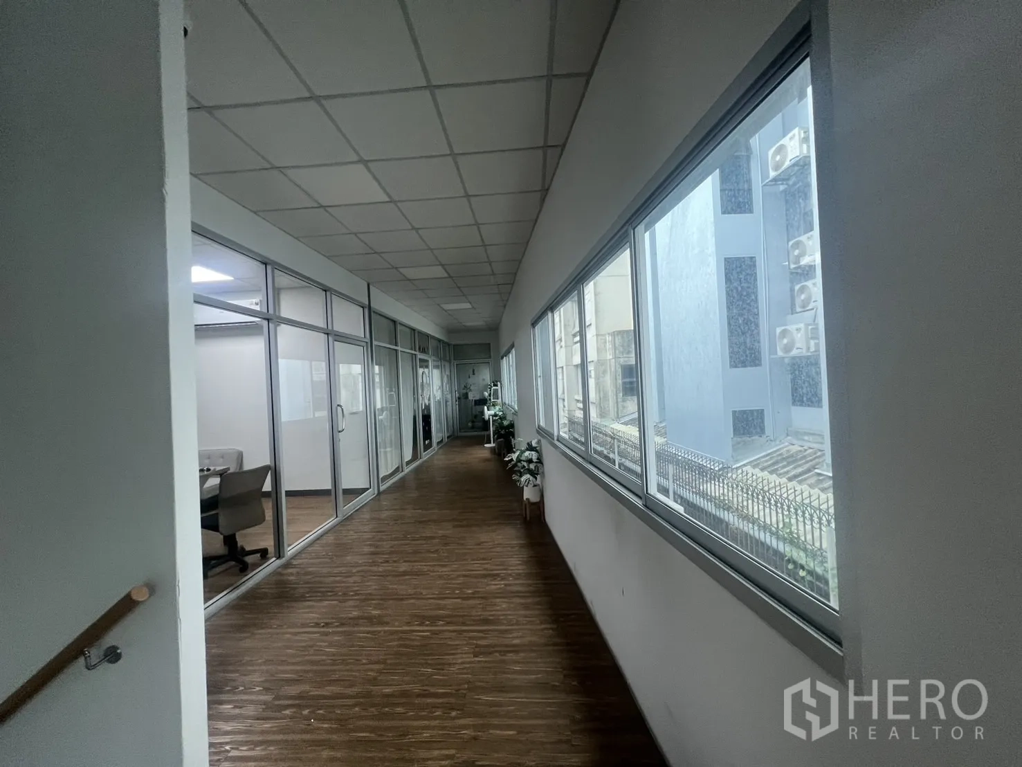 Retail Space for rent - Corridor with large windows and glass-partitioned offices beside the unit.