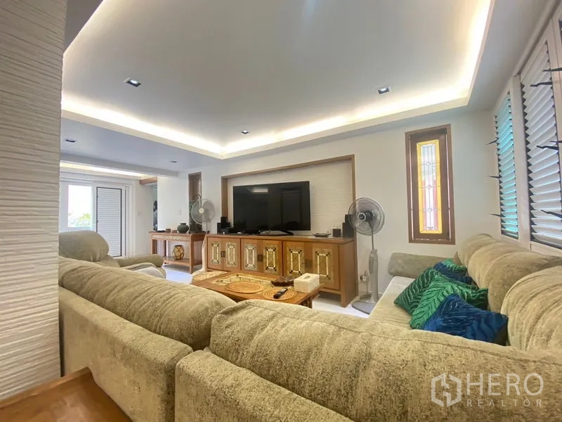 独立式住宅 出售在Khlong Toei, Bangkok - 明亮客厅，L形沙发、电视柜与灯槽顶。