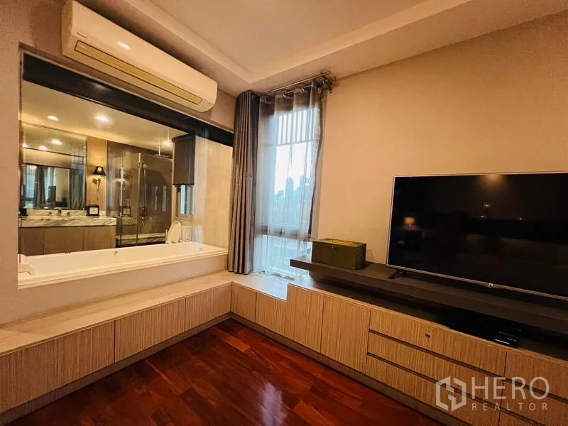 带办公室的家 出租在Khlong Toei, Bangkok - 卧室多媒体墙配大屏电视，窗户可见带浴缸的卫浴。