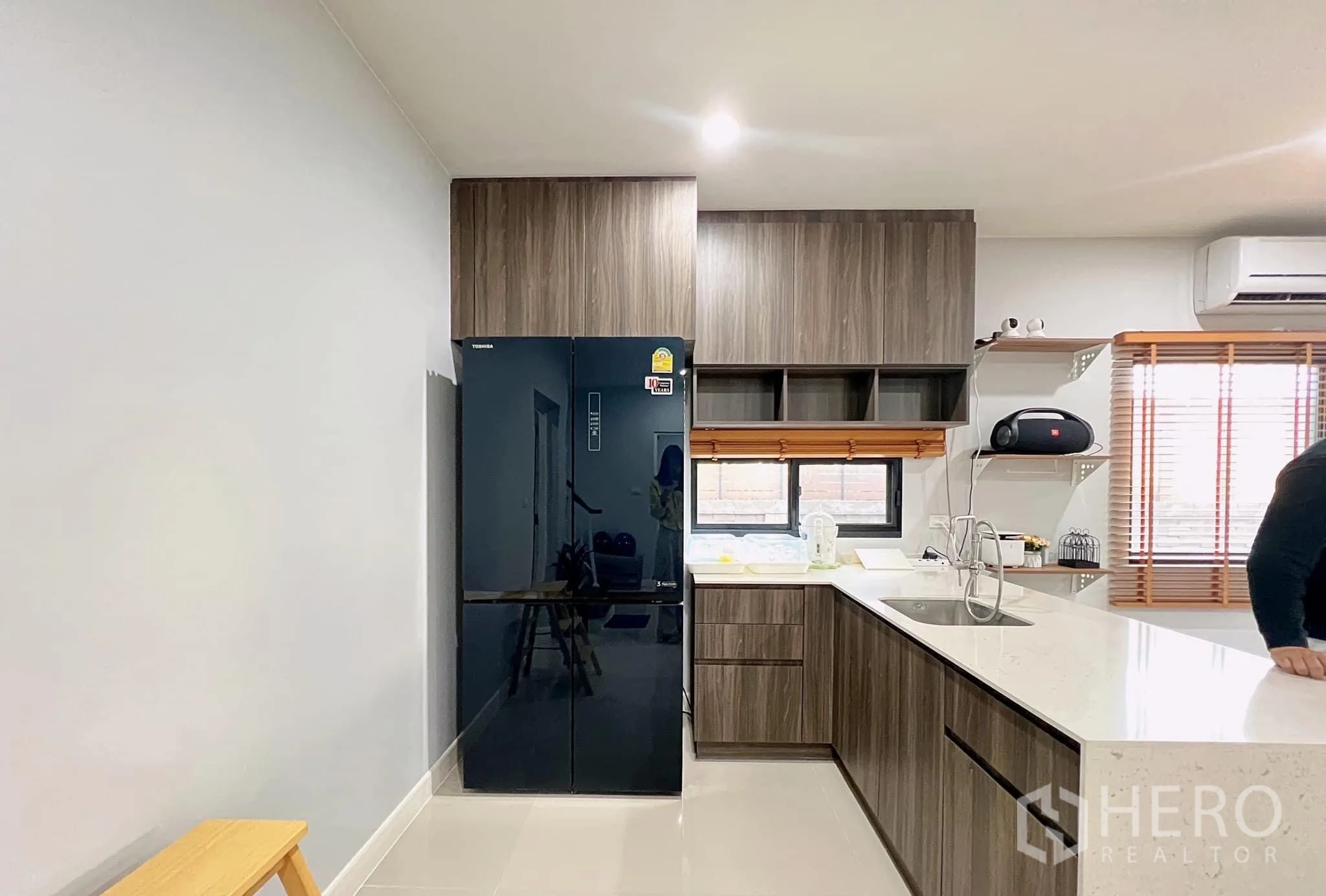 Detached House for rent or sale in Lam Luk Ka, Pathum Thani - L-shaped pantry with dark wood cabinets, quartz counter and black fridge.
