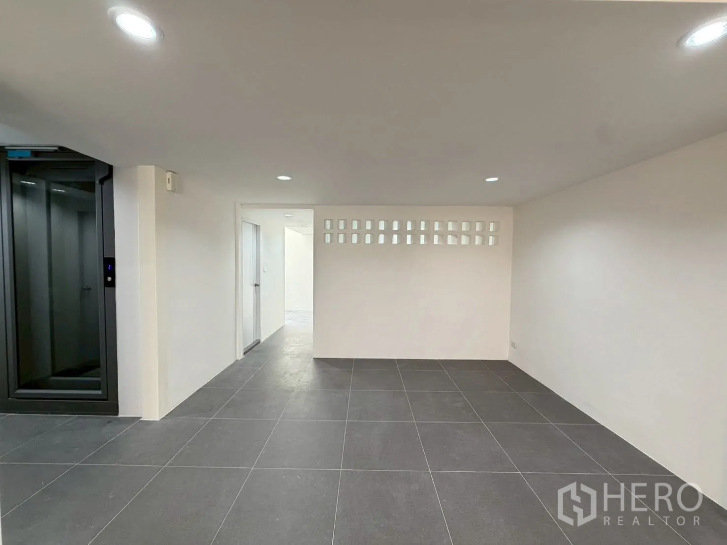 Townhouse for sale in Phra Khanong, Bangkok - Lower-level space with dark floor tiles and a lift, suitable for storage or office.