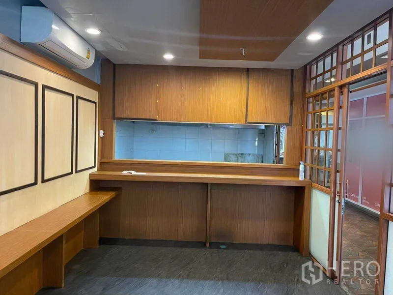 Retail Space for rent in Watthana, Bangkok - Front counter facing a pass-through to a tiled back room, wood paneling and a glass door to the corridor.