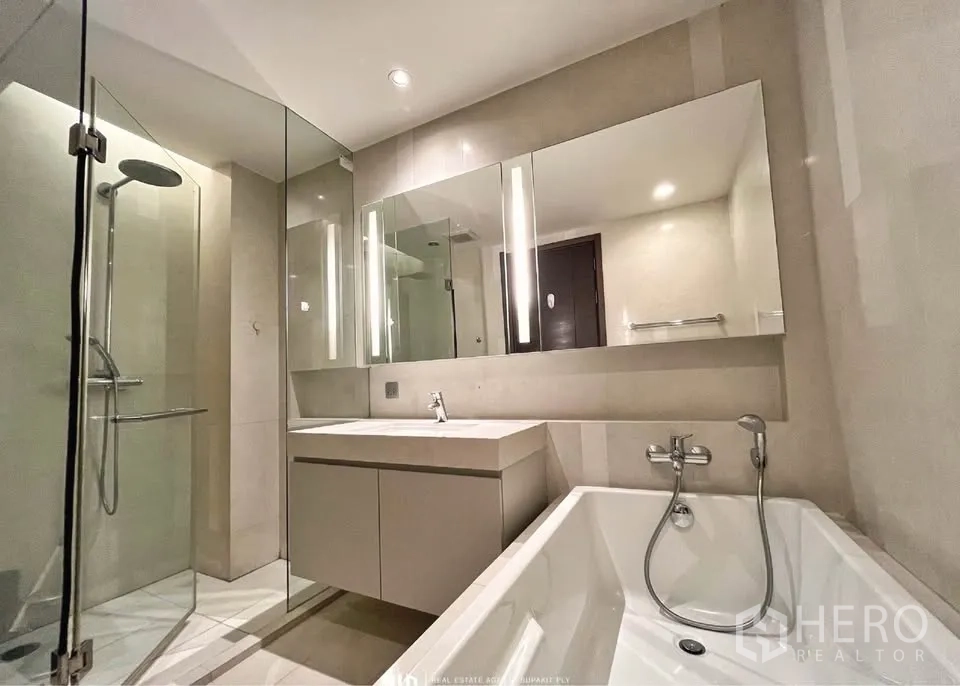 Condominium for rent in Watthana, Bangkok - Modern bathroom with glass shower, soaking bathtub and wide mirrored vanity.