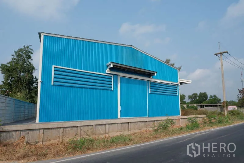 Warehouse for rent in Khlong Luang, Pathum Thani - Street-facing blue steel warehouse with raised loading dock and large sliding doors.