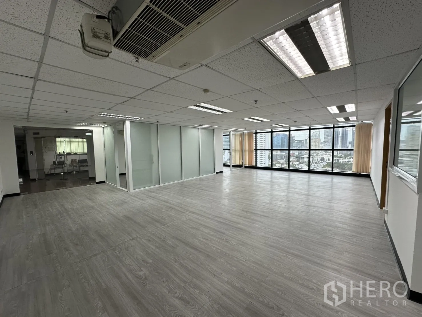 办公空间 出租在Watthana, Bangkok - 明亮办公区，木纹地板、嵌入式照明与玻璃隔断，俯瞰瓦他那区天际线。