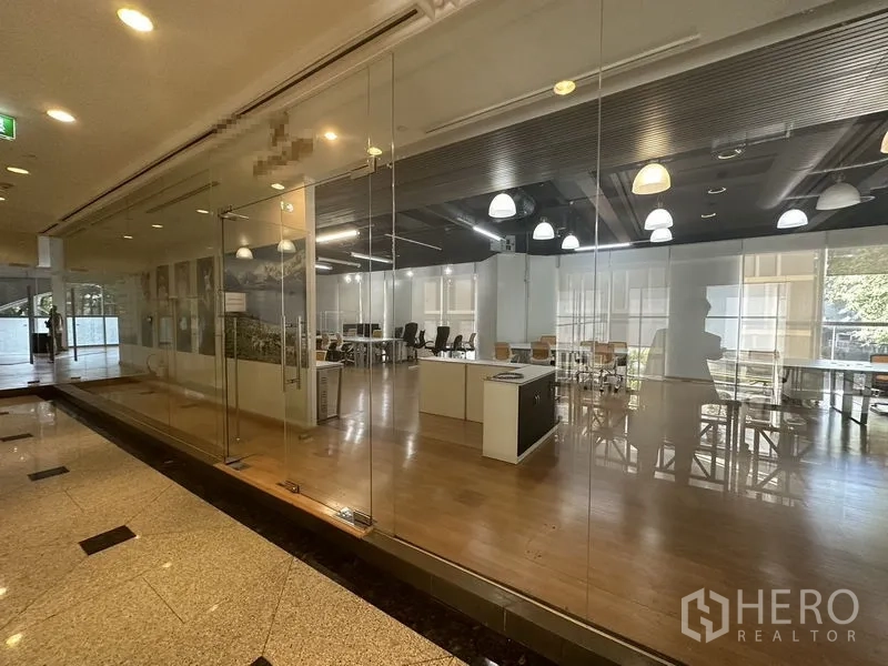 Office Space for rent in Pathum Wan, Bangkok - Open-plan workspace seen through full-height glass frontage from the corridor.