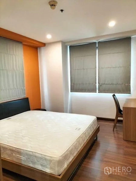 Condominium for rent in Watthana, Bangkok - Second bedroom with work desk, twin windows with blinds and wood flooring.