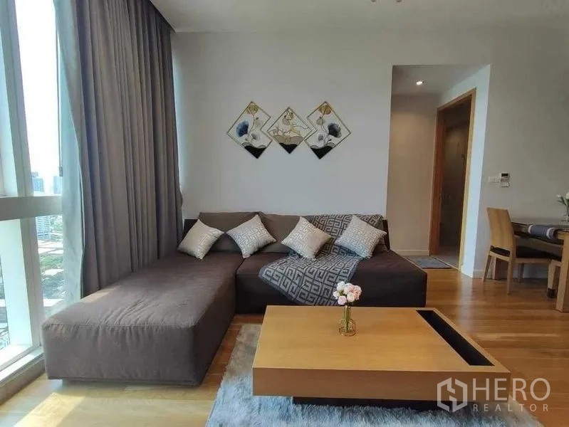 คอนโด ให้เช่าในKhlong Toei, Bangkok - ห้องนั่งเล่นอบอุ่น โซฟา L-Shape โต๊ะกลาง และงานตกแต่งผนัง