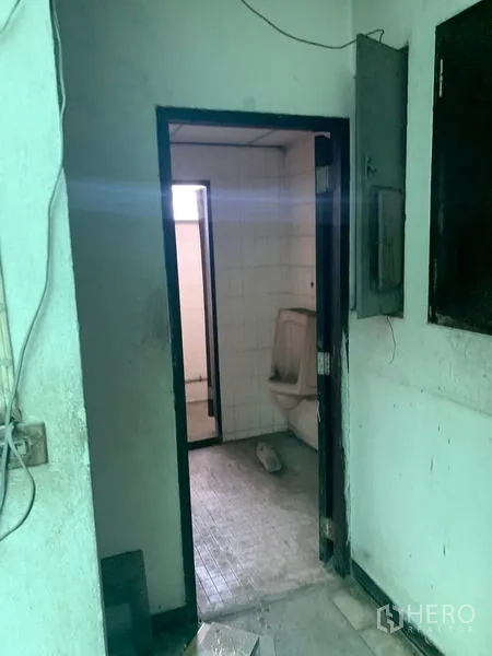 Shophouse for rent in Watthana, Bangkok - Small tiled bathroom beside an exposed electrical panel.