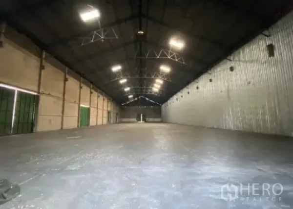 Warehouse for rent in Mueang Pathum Thani, Pathum Thani - Clear-span storage hall with steel roof trusses, metal wall cladding, and multiple loading doors.