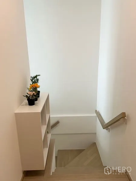 联排别墅 出租 - 木质楼梯配扶手与装饰搁架盆栽。