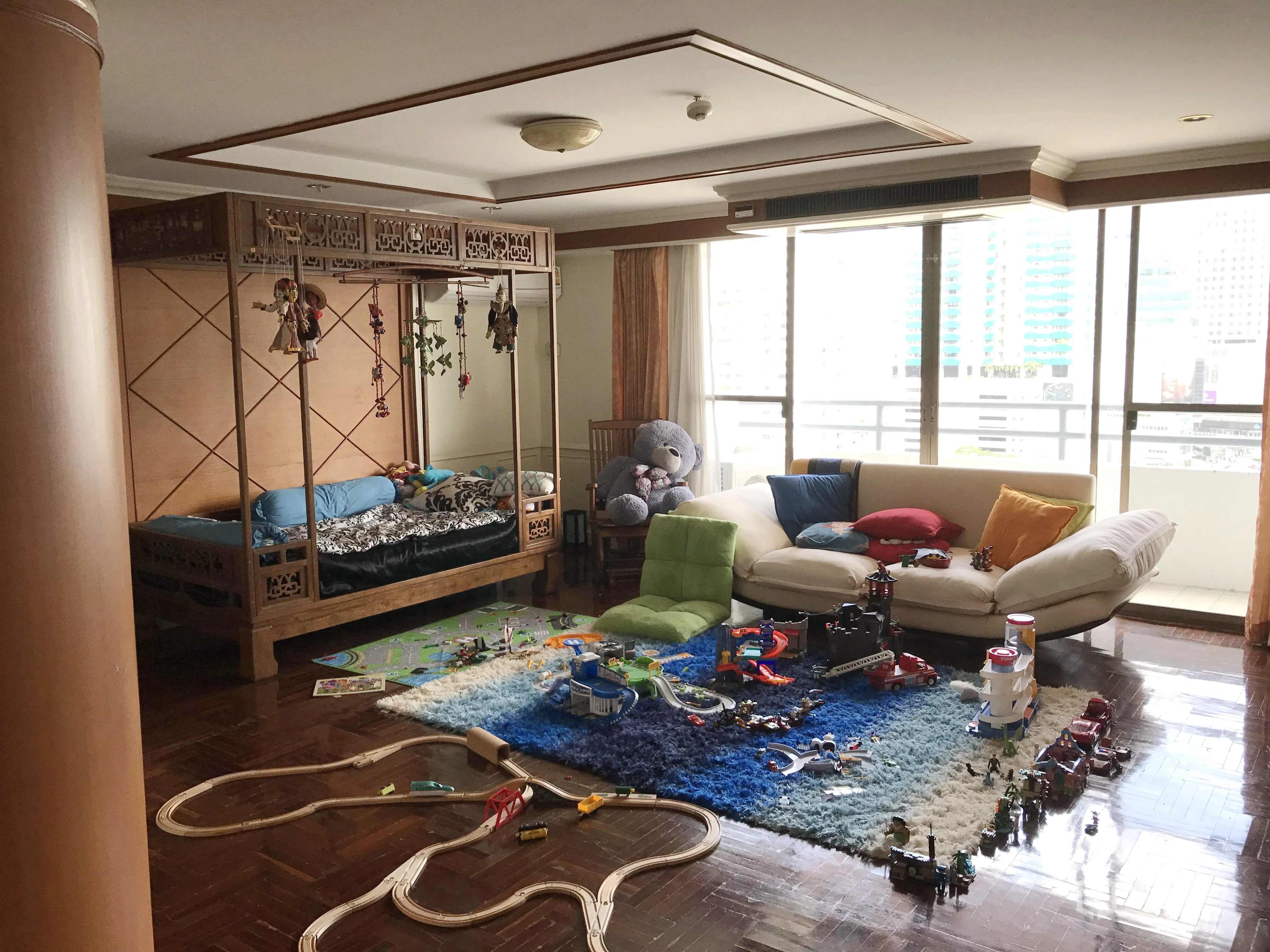 คอนโด ให้เช่าในWatthana, Bangkok - ห้องนอนหรือห้องครอบครัวขนาดใหญ่ เตียงสี่เสา หน้าต่างสูงจรดเพดาน ระเบียงมองเห็นเมือง และมุมเด็กเล่นบนพรมสีสัน
