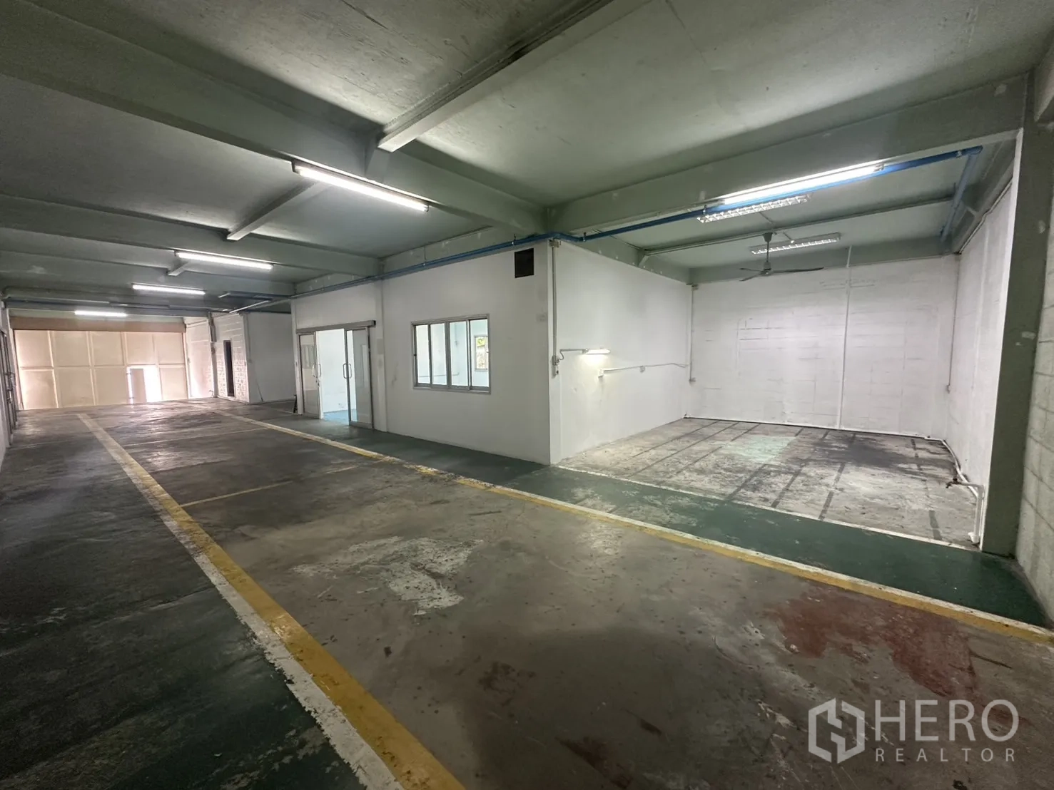 Warehouse for rent in Bang Na, Bangkok - Open work bay beside corridor under strip lighting.