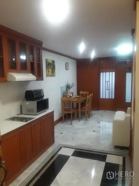公寓 出租在Watthana, Bangkok - 开放式厨房带木柜、灶台与餐桌，大理石地面
